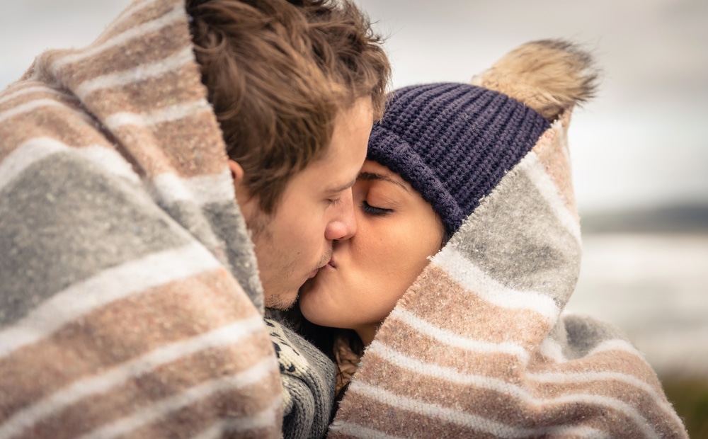 A young couple sneaks a kiss under a blanket during one of the most romantic getaways in New Mexico.